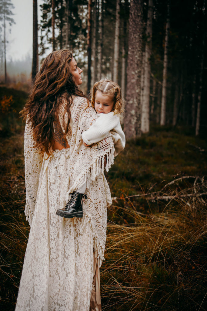 Mor og datter i skogen med kjoler.