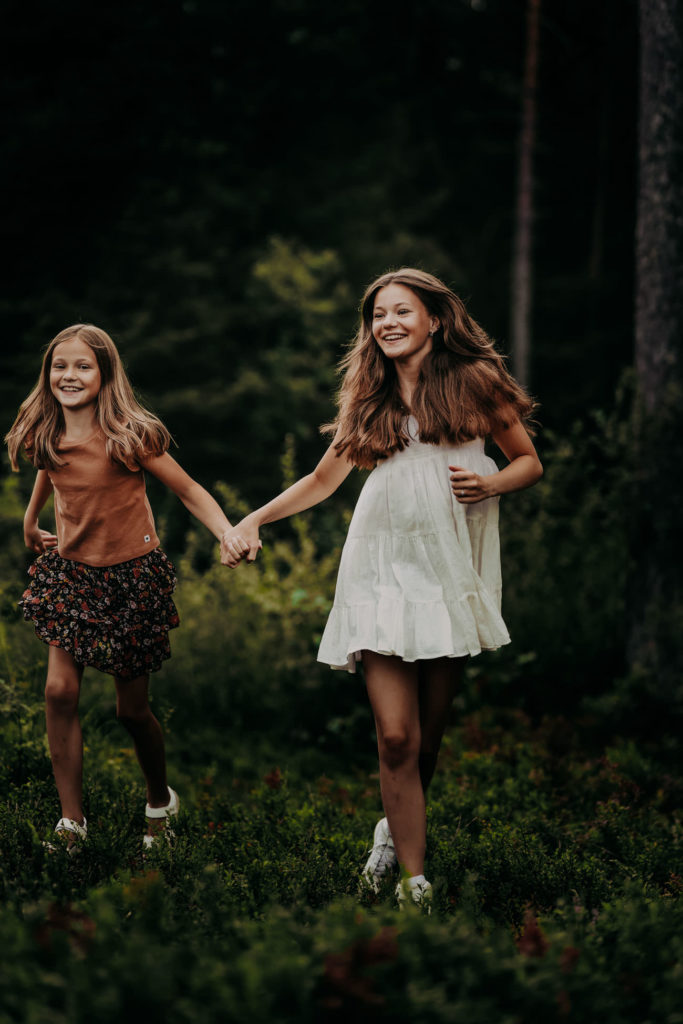 To jenter som løper barbeint i skogen.